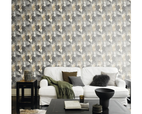 Vardagsrum med soffa framför en vägg med blad tapet