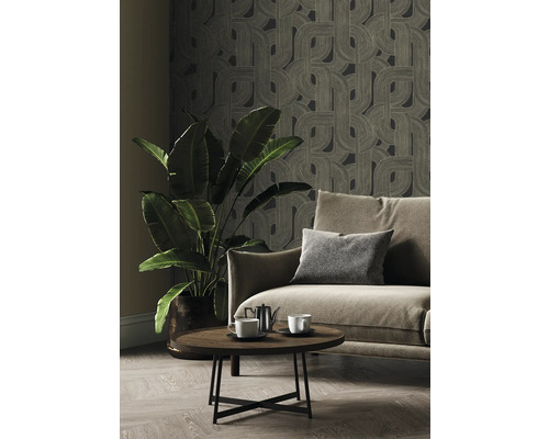 Vardagsrum med mönstrad tapet, soffa, bord och krukväxt