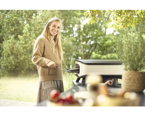 Kvinna grillar på en bordsgrill i trädgården.