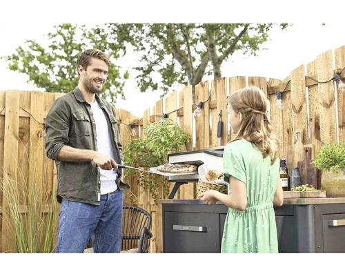 Man och flicka förbereder pizza i utomhuspizzaugn på terrassen