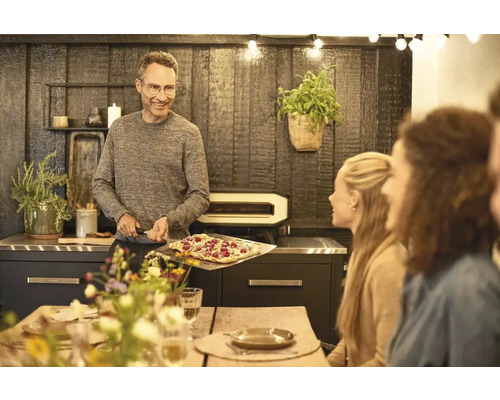 Man med pizza framför pizzaugn i matsalen
