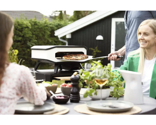 Pizza ugn i trädgården med människor som äter
