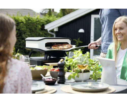 Pizza ugn i trädgården med folk som bakar pizza