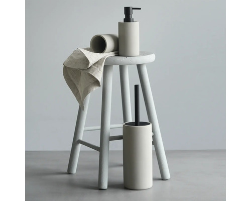 Badrumstillbehörsset på en pall, bestående av en tvålpump, tandborstmugg, toalettborste och handduk