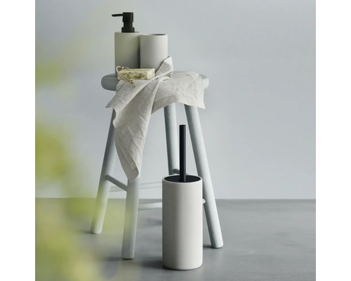 Badrumsstilleben med tvålpump, mugg, tvål, handduk och toalettborste på en pall