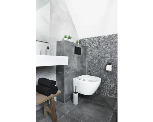 Modernt badrum med vägghängd toalett, handfat och träpall.