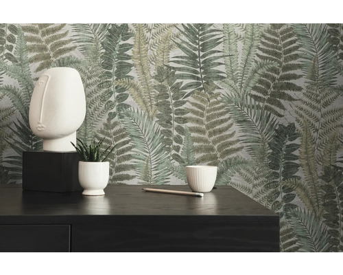 Dekorativ inredning med tapet med ormbunksmönster, skulptur, växter och mörk byrå