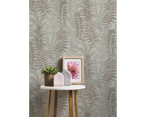 Rum med tapet med ormbunksmönster, sidobord, krukväxt och fotoram