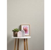 Rumsöversikt med beige tapet, bord, växt och dekoration