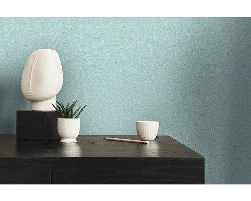 Ljus, strukturerad non-woven tapet på en vägg bredvid en byrå med dekorationer.