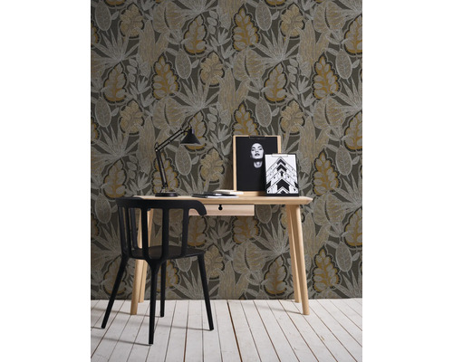 Rumsöversikt med skrivbord, stol, lampa och tapet med bladmönster