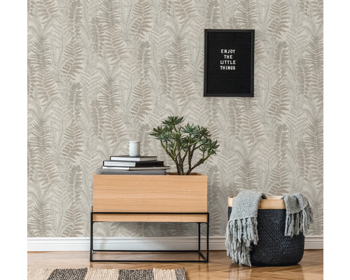 Vardagsrum med mönstrad tapet, växt och dekoration för en mysig atmosfär.