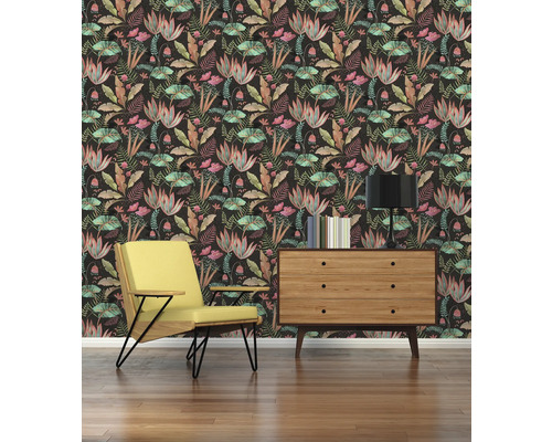 Vardagsrum med gul fåtölj, byrå, lampa och blommig tapet