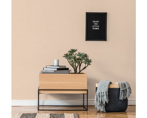 Ljust rum med trägolv, byrå, krukväxt, korg och väggdekoration