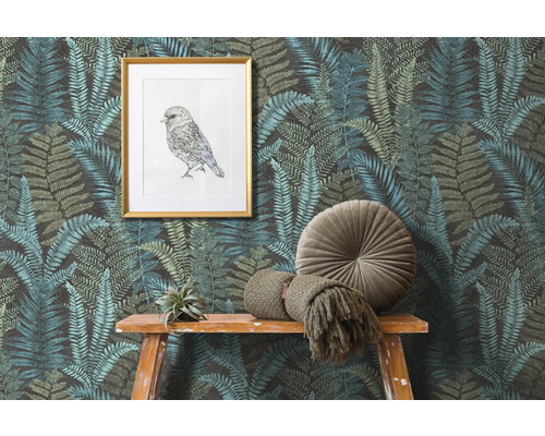 Scen med tapet med ormbunksmönster, en inramad fågelbild och dekorationer på ett träbord