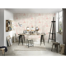 En ljus studio med mönstrad tapet, ett träbord och diverse konstnärsmaterial.