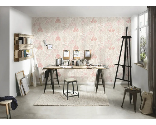 En ljus studio med mönstrad tapet, ett träbord och diverse konstnärsmaterial.