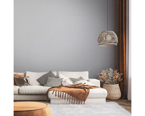 Ljust vardagsrum med soffa, kuddar, filt och dekorationer i en naturlig design