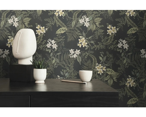 Dekorativt stilleben med blommig tapet, skulptur och växt på byrå