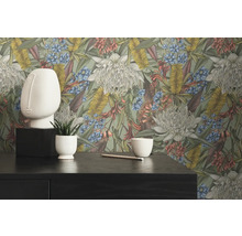 Dekorativ interiör med blomstertapet, ansiktsskulptur och växt i kruka på ett mörkt bord.