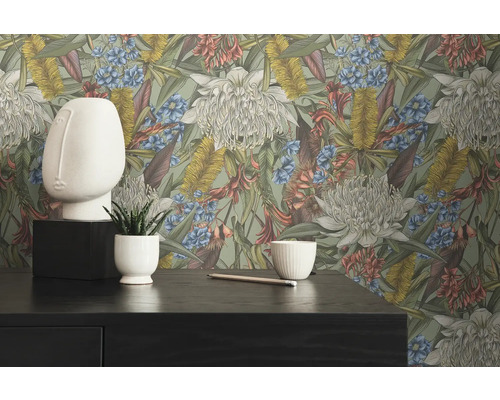 Dekorativ interiör med blomstertapet, ansiktsskulptur och växt i kruka på ett mörkt bord.