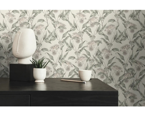 Scen med en byrå, en vit ansiktsskulptur och tapet med ett blommönster.