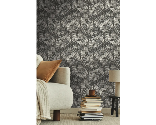 Scen med en väggtapet med växtmönster, en soffa och en stapel böcker