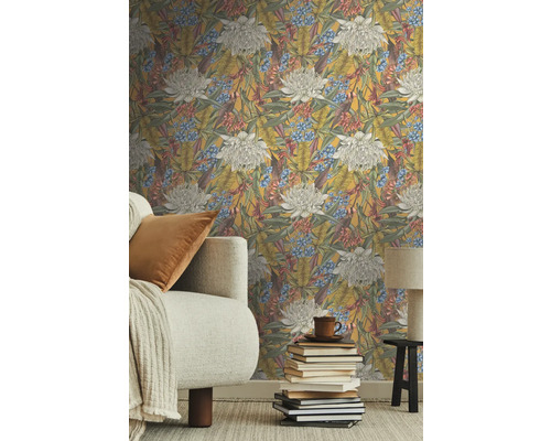 Vardagsrum med blommig non-woven tapet, soffa och bokstapel.