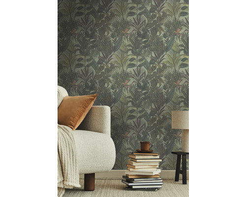 Rum med djungeltapet, soffa, kudde, lampa och bokstapel.