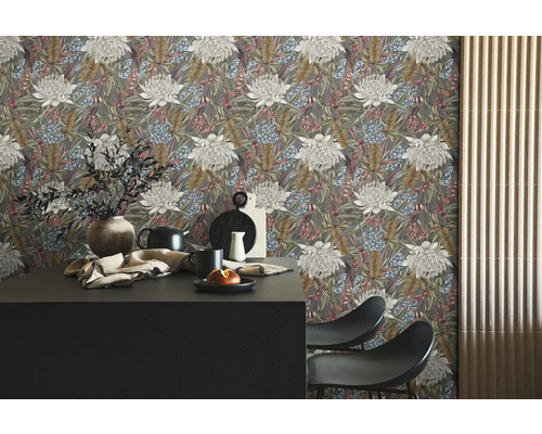 Vardagsrum med blommig tapet, bord och stolar.