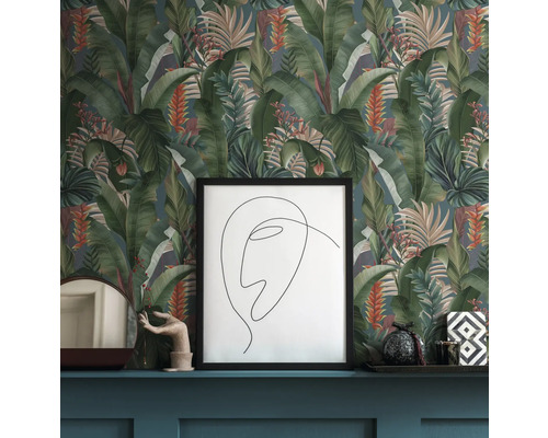 Scen med mönstrad tapet med tropiska blad, en inramad bild och dekorativa föremål på en hylla