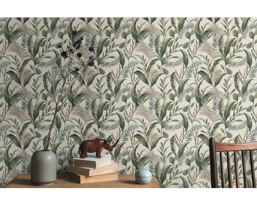 Scen med en blommig tapet med tropiska blad, ett träbord, en vas, böcker och en noshörningsfigur