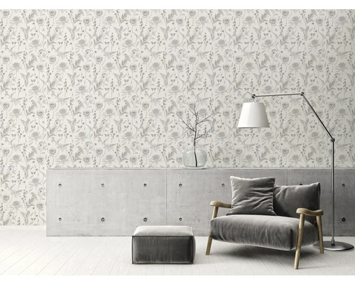 Rumsbild med en tapet med blommönster, en fåtölj, en golvlampa och ett soffbord.
