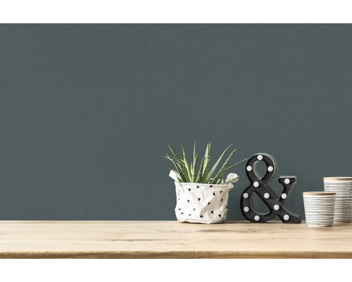 Närbild av en väggtapet med krukväxt, dekorativt tecknet och två muggar på ett bord