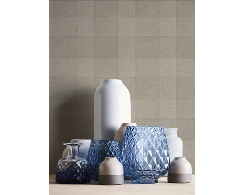 Dekorativa vaser i olika former och material framför en mönstrad tapet.