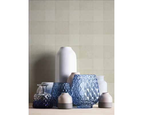 Dekorativa vaser av glas och keramik framför en beige tapet med rutmönster.