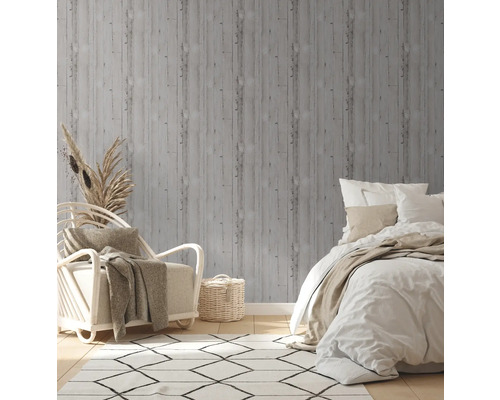 Dekorativt sovrum med grå tapet i träutseende, fåtölj och säng