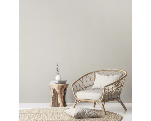 Ljus inredning med rottingfåtölj, rund matta och sidobord i trä.