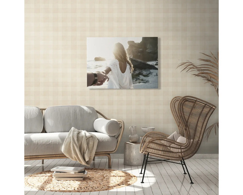 Vardagsrum med soffa, rottingfåtölj och väggbild med strandmotiv