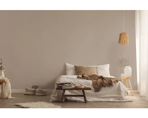 Ljust sovrum med säng, träpall och taklampa i rotting för en vänlig atmosfär.
