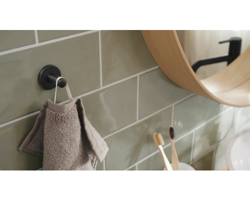 Detalj av ett badrum med handdukskrok, handduk, spegel och tandborstar