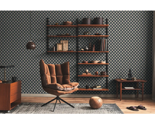 Vardagsrum med mönstrad tapet, hyllor, fåtölj, matta och trägolv.