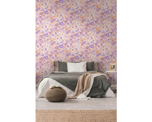 Sovrum med blommig tapet, säng, överkast, sidobord och matta