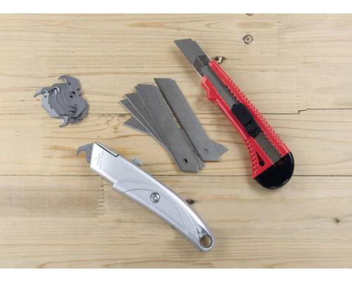 Två brytbladsknivar och blad på träunderlag