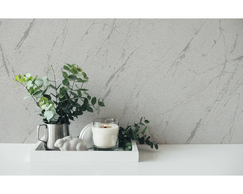 Dekorativ scen med krukväxt, ljus och marmortapet