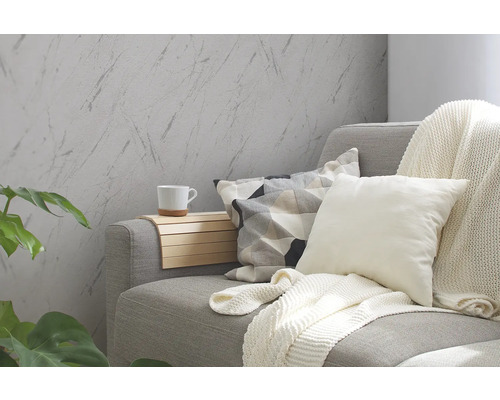 Vardagsrum med grå soffa, kuddar, filt och väggbeklädnad i marmorlook