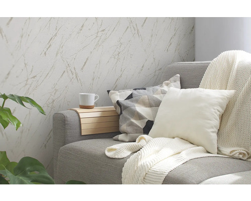 Vardagsrum med grå soffa, kuddar, filt, sidobord och tapet med marmormönster.