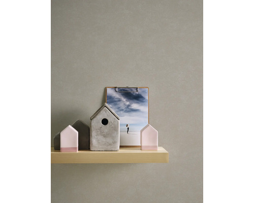 Dekorativa hus av betong och trä på en hylla, med en bildbräda i bakgrunden