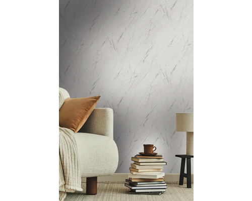 Vardagsrum med mönstrad tapet, soffa, böcker, bordslampa och matta för en mysig atmosfär