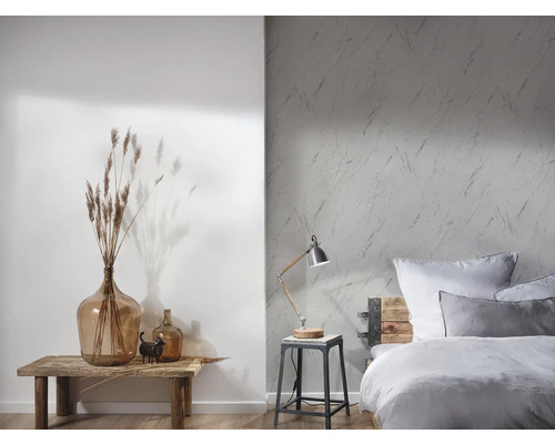 Ljust sovrum med mönstrad tapet, trä säng och dekorativa element på ett träbord